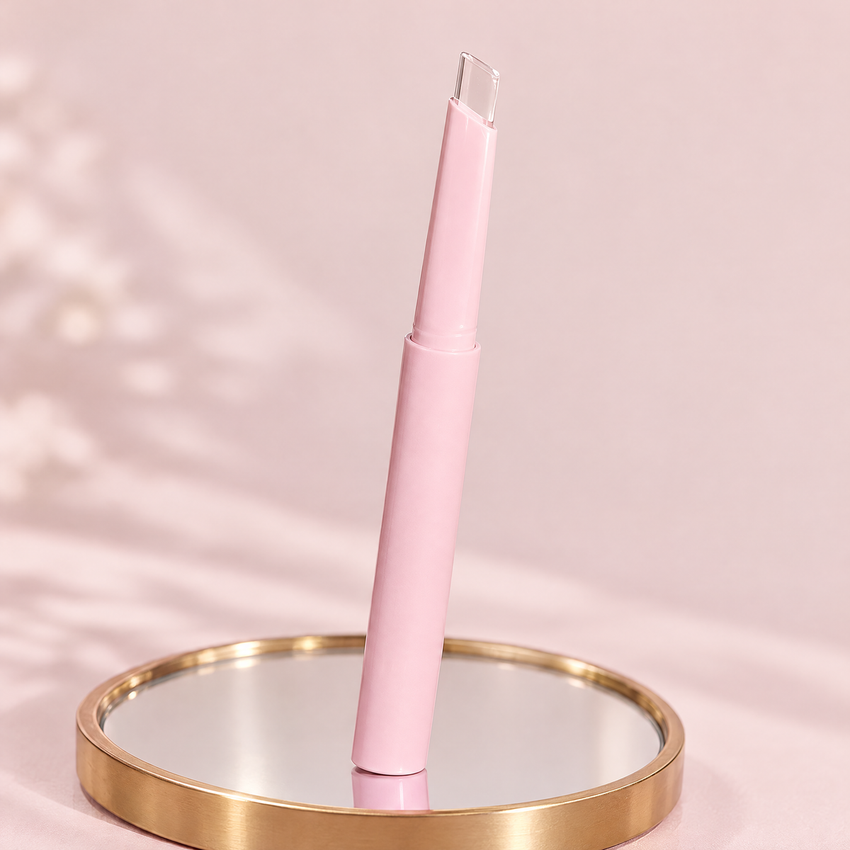 Clear lip liner pen with transparent angled tip standing on a gold-rimmed mirror tray against a blush pink backdrop